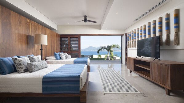 Un dormitorio moderno con una cama grande, televisión y vista al océano.
