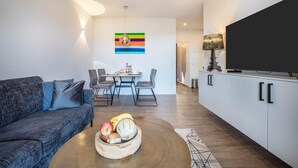 Ein modernes Wohnzimmer mit Sofa, Esstisch und Fernseher.