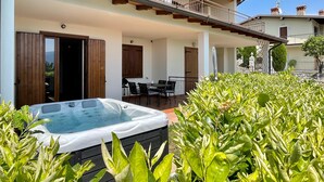 Ein zweistöckiges Gebäude mit Balkon, Whirlpool und einer Terrassenanlage mit Stühlen und Tischen.