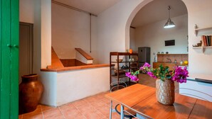 A kitchen with a wooden table, a vase with flowers, and a staircase.