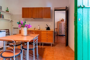 A kitchen with wooden cabinets, a dining table with chairs, and a green door.