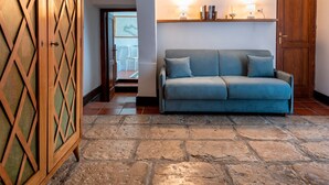 A room with a stone floor, a blue sofa, a wooden cabinet, and a door.