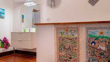 A bathroom with a mirror, a sink, a toilet, and a decorative wall with two colorful murals.