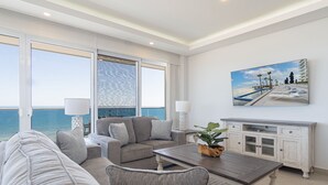 Een moderne woonkamer met uitzicht op de oceaan, een bank, een salontafel en een kast.