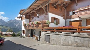 A wooden building with balconies, stone walls, and a mountain view.
