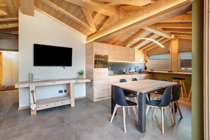 Una cocina moderna con vigas de madera, horno empotrado y comedor con mesa y sillas de madera.