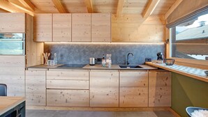 Una cocina moderna con armarios de madera, encimera negra y ventana con vistas a un paisaje montañoso.