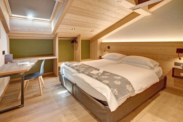 A bedroom with a bed, a desk, and a chair.