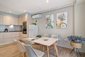 Een moderne keuken met een magnetron, koelkast en eethoek met stoelen en een tafel.