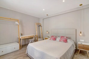 Een slaapkamer met een bed, nachtkastjes, een bureau en een kledingkast.