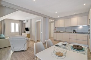 A modern apartment with a dining area, kitchen, and living room.