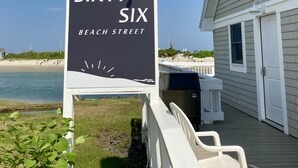 A sign for 'Sixty Six Beach Street' with a view of the beach and a building in the background.