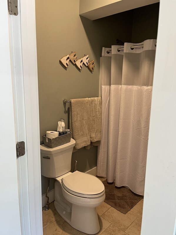A bathroom with a toilet, a shower curtain, and a towel rack.