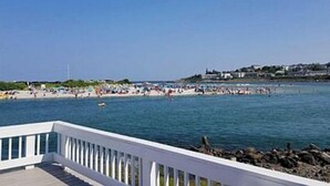 A coastal view with a white pier leading to a beach.