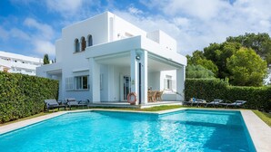 A modern white building with a swimming pool, lounge chairs, and a lifebuoy. - Villa 'Sa Caleta de Cala D'Or' with Sea View, Pool, 2 Terraces & Wi-Fi (Santanyí)