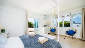 A bedroom with a bed, a chair, a dresser, and a window with a view. - Villa 'Sa Caleta de Cala D'Or' with Sea View, Pool, 2 Terraces & Wi-Fi (Santanyí)