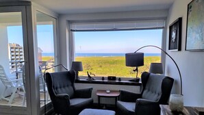 A room with a view of the sea, two armchairs, a small table, and a lamp. - House Brandenburg App. 43 with lake view - 2 room apartment with breathtaking views (Sylt)