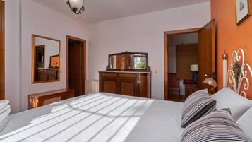 A hotel room with a bed, a dresser, a mirror, and a door leading to another room.