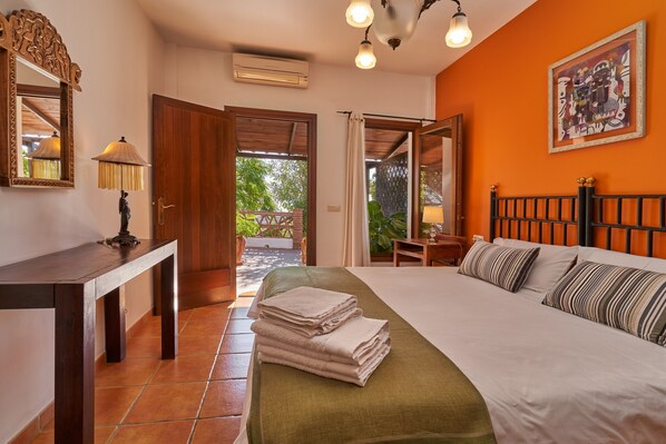 A hotel room with a bed, a desk, a mirror, a lamp, and a view of the outdoors.