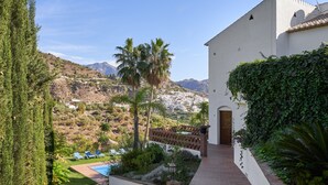A pool area with lounge chairs, a pathway, and a view of a town and mountains.