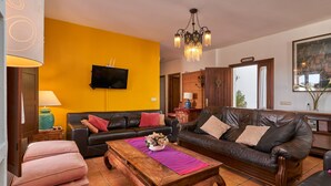 A living room with a wooden coffee table, two sofas, a TV, and a chandelier.