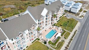 Un hotel de varios pisos con piscina, mobiliario exterior y vistas del entorno.