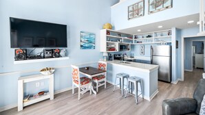Una cocina moderna con una isla central, armarios blancos y un televisor de pantalla plana montado sobre la isla.