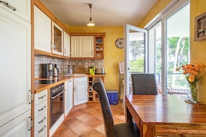 A compact kitchen with white cabinets, a wooden countertop, and a dining area with a table and chairs.