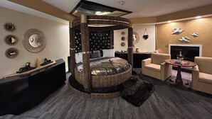 A bedroom with a circular canopy bed, a round coffee table with drinks, and a fireplace. - Inn of The Dove Harrisburg-Hershey Romantic Suites (Harrisburg)