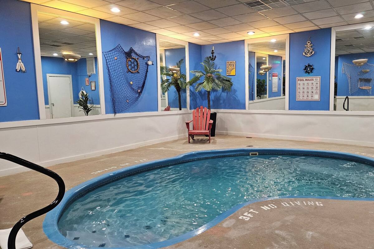 Une piscine intérieure dotée d’un plongeoir, d’une chaise rouge et d’un panneau indiquant une profondeur de 3 pieds pour la plongée.