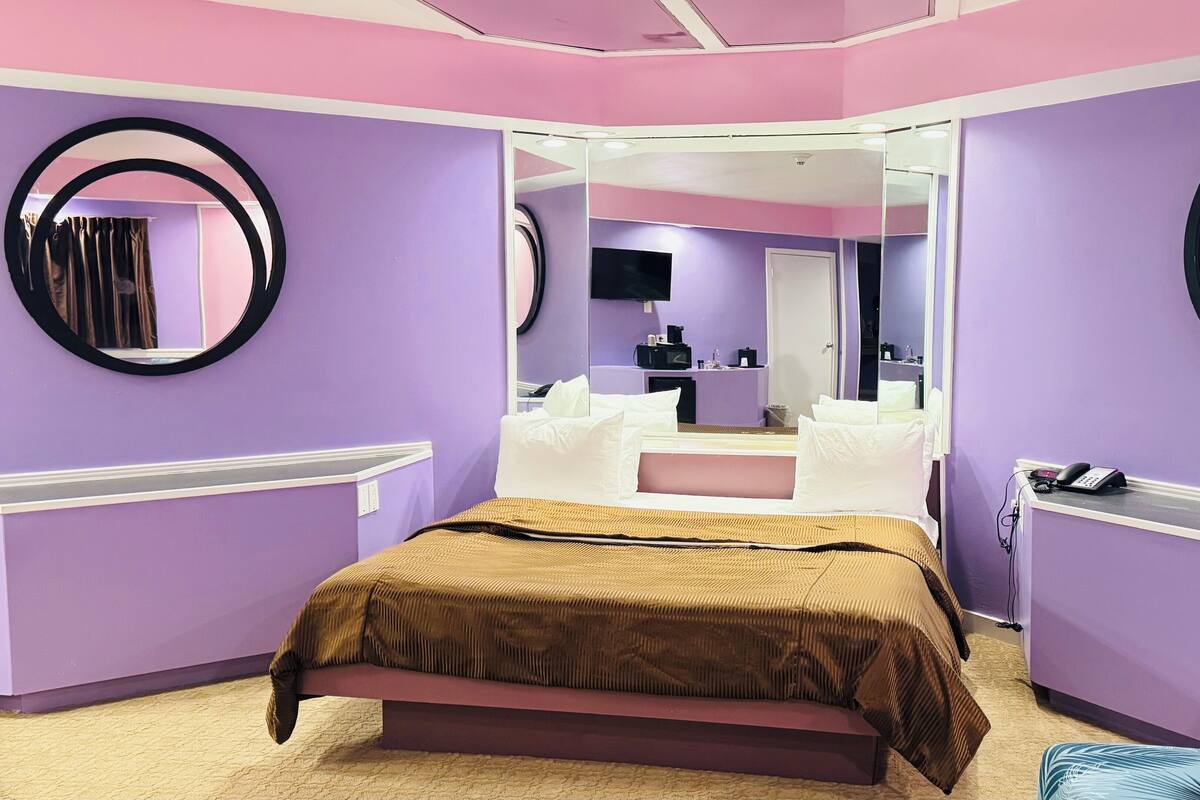 Une chambre à coucher avec un lit, un miroir, un bureau et une chaise.