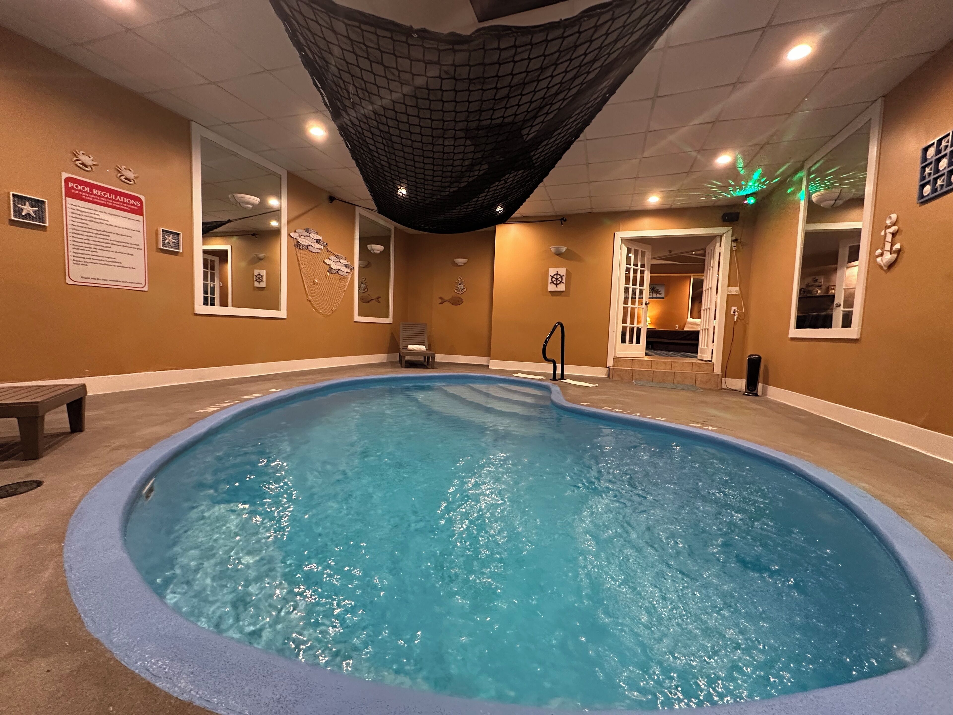 An indoor swimming pool with clear water, a bench, and a chair.