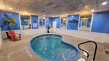 An indoor swimming pool with blue walls, a red chair, and a pool rule sign.