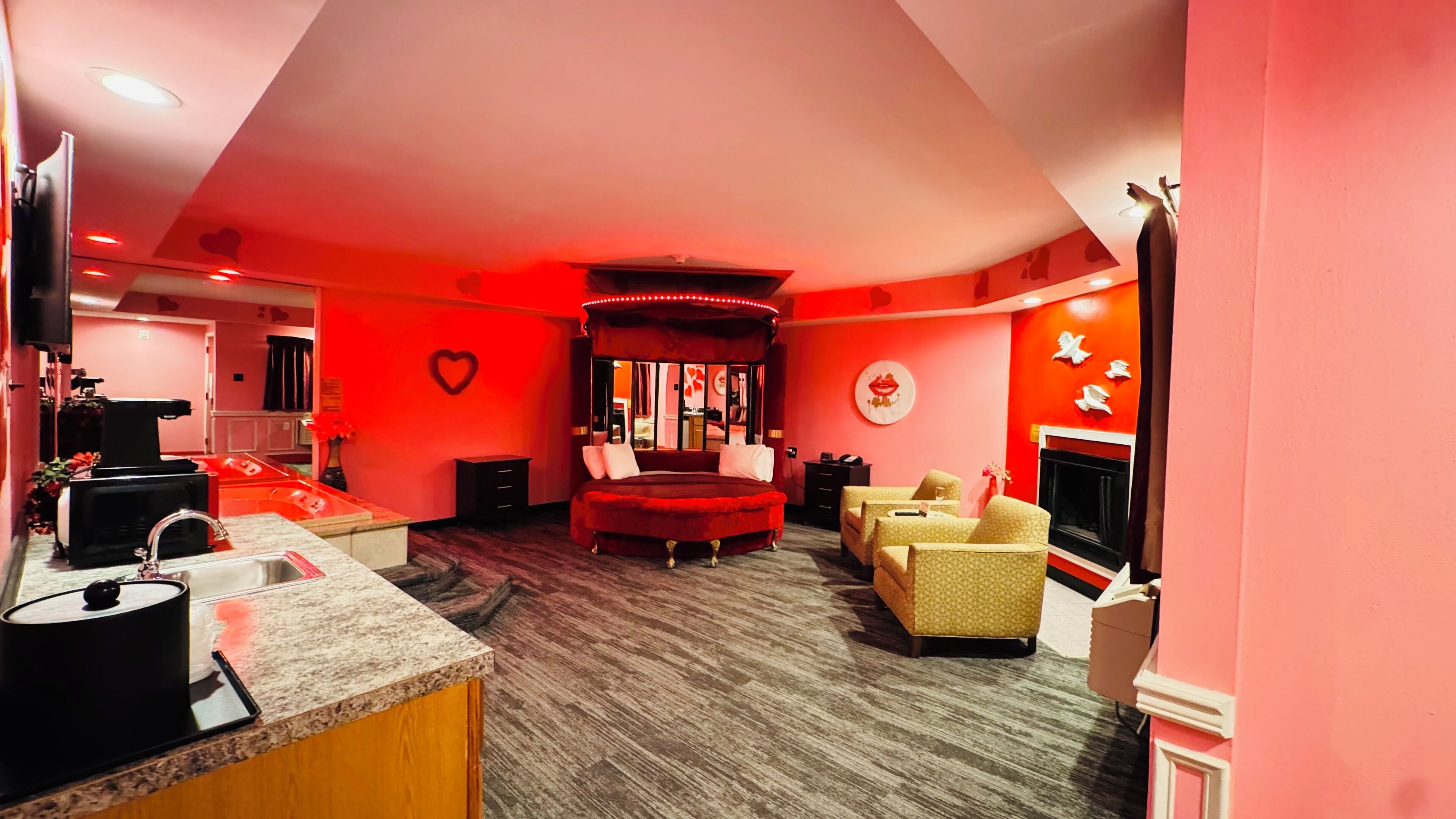 Une pièce décorée dans les tons de rouge, comprenant un lit, une cheminée et un coin salon.