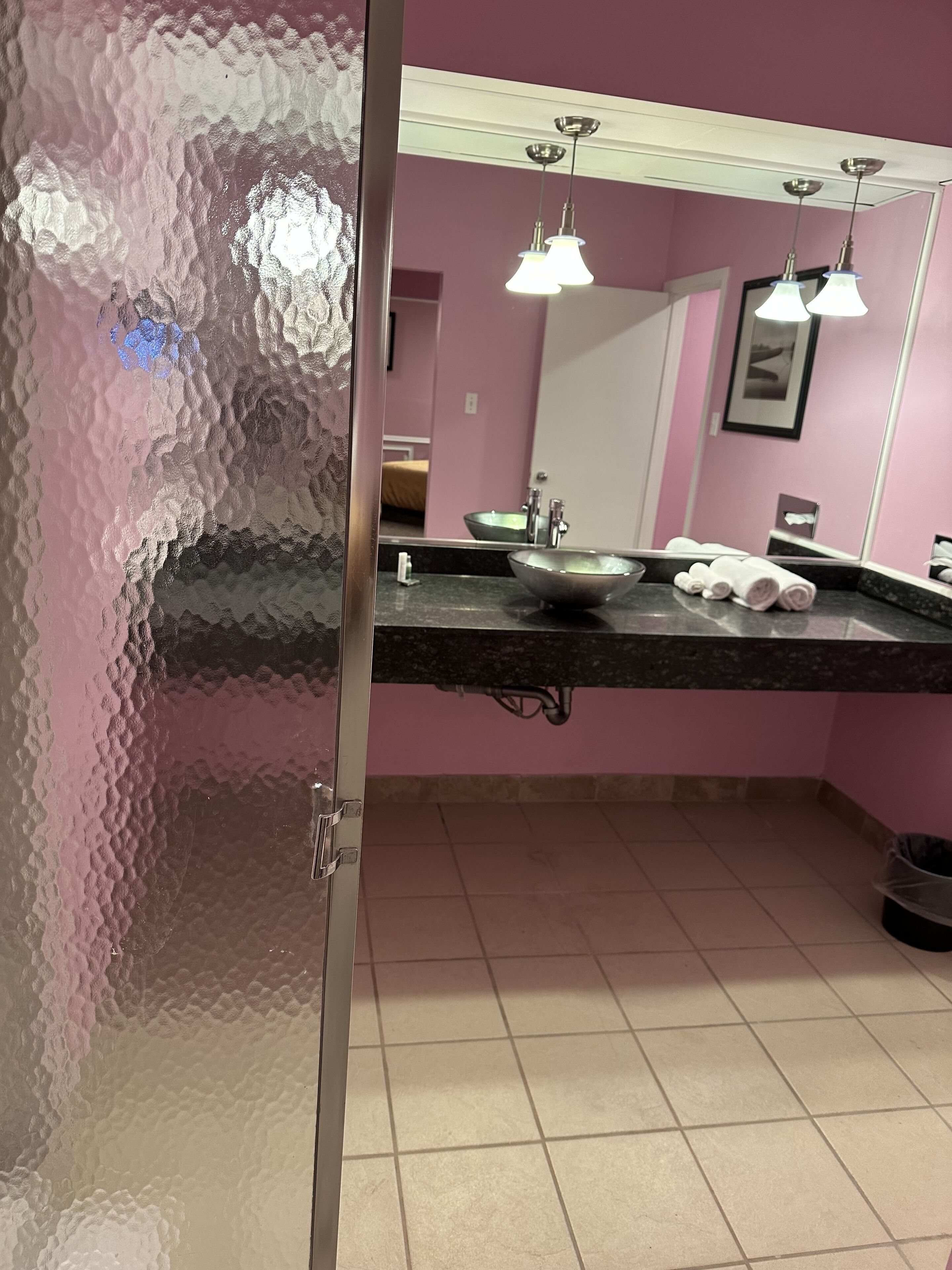 A bathroom with a large mirror, a sink, and two pendant lights.