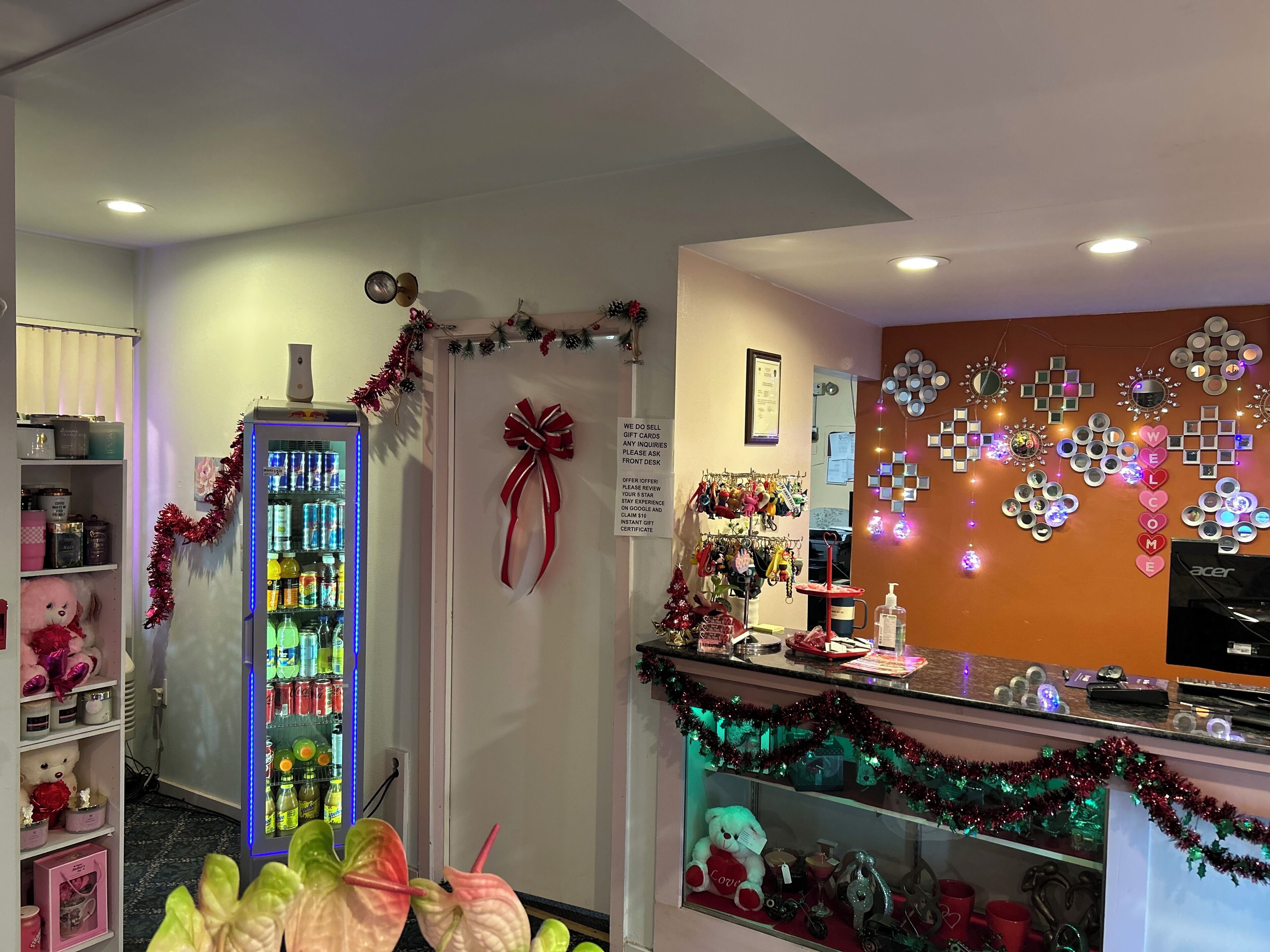 A hotel reception area with a vending machine, a counter with various items, and a wall decorated with lights and mirrors.