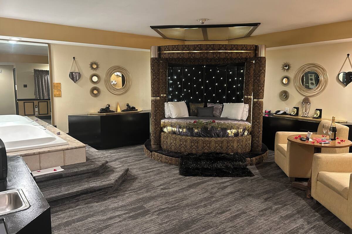 Une chambre à coucher avec un grand lit, une coiffeuse avec un miroir, un bureau et une chaise.