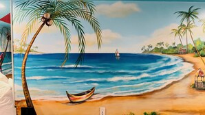 A beach scene with palm trees, a boat, and a sailboat on the water. - Inn of The Dove Harrisburg-Hershey Romantic Suites (Harrisburg)