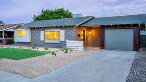 A single-story house with a garage, a well-maintained lawn, and a driveway leading to the front door. - Quiet Oasis in Old Town Scottsdale (Scottsdale)