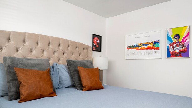 A bedroom with a tufted headboard, a bed with blue bedding, and two brown pillows. There are two framed pictures on the wall. - Quiet Oasis in Old Town Scottsdale (Scottsdale)