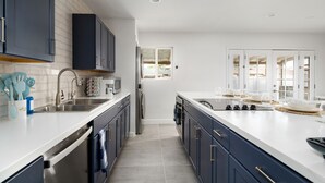 A modern kitchen with stainless steel appliances, a white countertop, and blue cabinets. - Quiet Oasis in Old Town Scottsdale (Scottsdale)