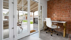 A room with a white desk, a white office chair, and a brick wall. - Quiet Oasis in Old Town Scottsdale (Scottsdale)