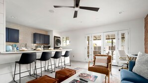 A modern kitchen with dark cabinets, a central island, and a dining area with bar stools. - Quiet Oasis in Old Town Scottsdale (Scottsdale)