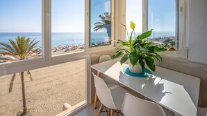 A balcony with a view of the beach and ocean, a dining table with chairs, and a potted plant. - Estudio Medayra by Solset (Torrox)