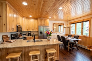 A kitchen with wooden cabinets, a stainless steel refrigerator, a microwave, and a sink.