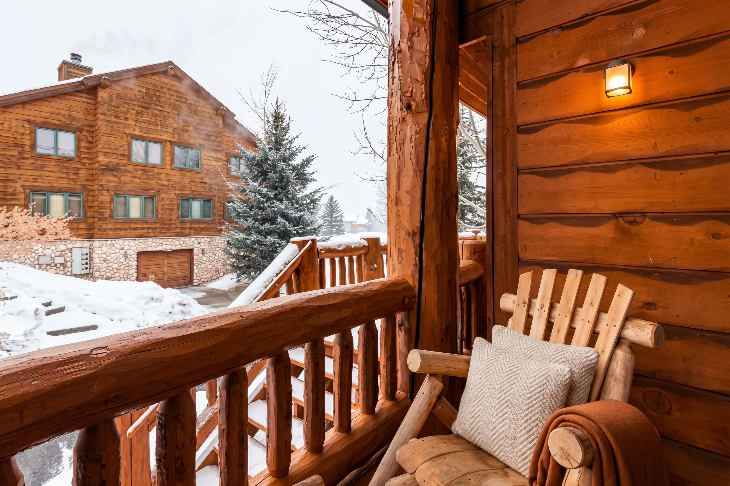 Eine Holzlaube mit Balkon, einer Steinmauer und einer schneebedeckten Landschaft.