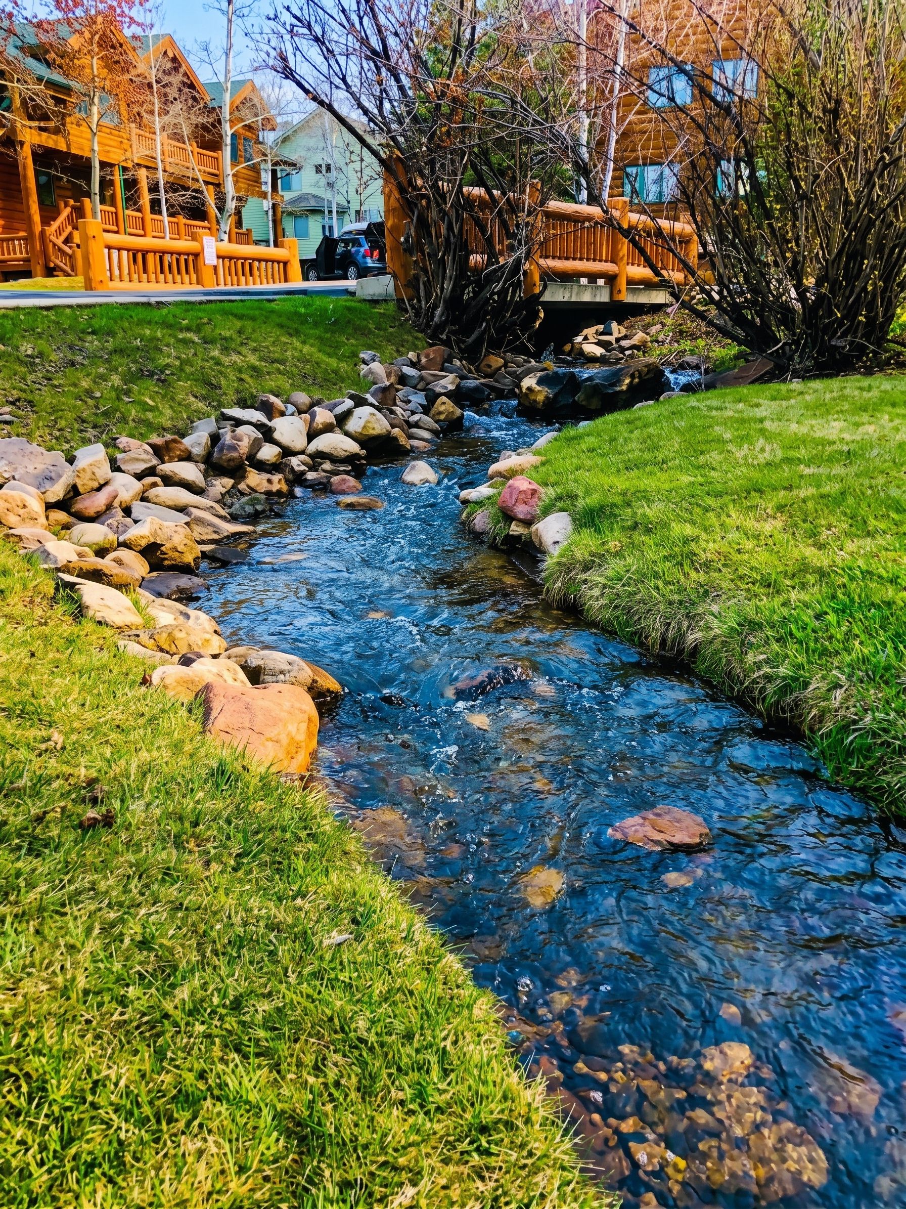 The clear stream, rocky banks, and rustic wooden bridge.