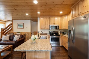 A modern kitchen with wooden cabinets, stainless steel appliances, and a granite countertop.