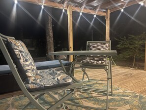 Un espace extérieur aménagé avec une table et des chaises, un coussin à motifs et une terrasse en bois.