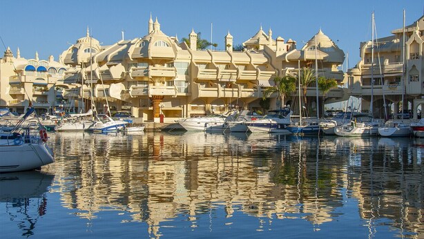 Un port de plaisance où sont amarrés de nombreux yachts, entouré de bâtiments aux conceptions architecturales originales.